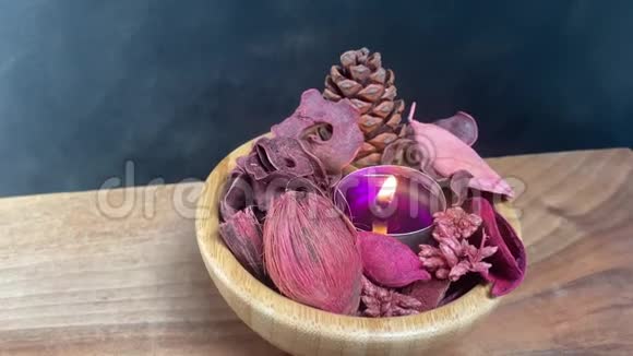 紫色茶灯和干锅放在木碗里放在黑色背景的桌子上视频的预览图