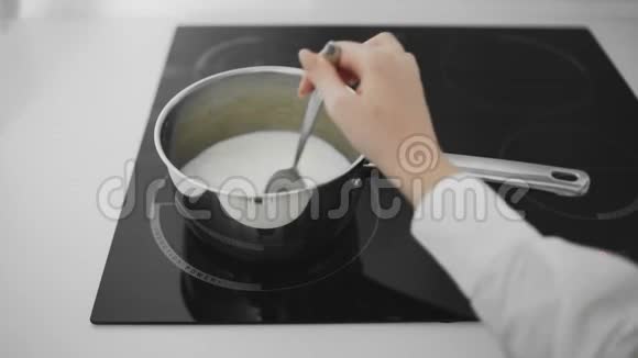 牛奶在平底锅里沸腾女人用平底锅搅拌牛奶视频的预览图
