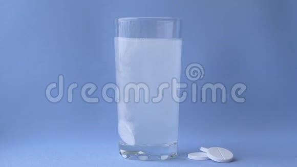 阿司匹林溶解在一杯水上的蓝色背景特写视频的预览图