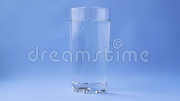 阿司匹林溶解在一杯水上的蓝色背景特写视频的预览图