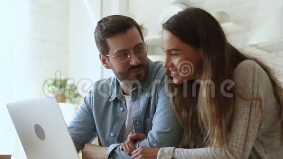 幸福的年轻一家夫妻在说笑玩手提电脑视频的预览图