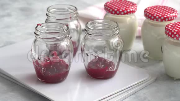 用牛奶混合物灌装玻璃瓶生产自制酸奶罐子底部的覆盆子果酱视频的预览图