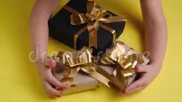 儿童的手的俯视图在彩色黄色背景上放置各种礼品盒圣诞节新年生日概念视频的预览图