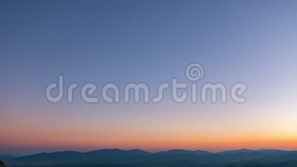 白天到夜晚的时间流逝美丽的橙色和紫色的日落黄昏景象在高山之上转向夜景有许多视频的预览图