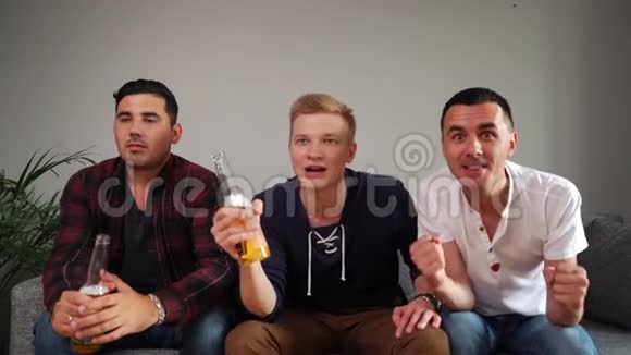男伴三个朋友在家电视上有感情地看体育比赛视频的预览图