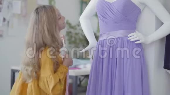 漂亮的小女孩穿着优雅的紫色连衣裙挂在房间里的人体模型上孩子学缝纫视频的预览图