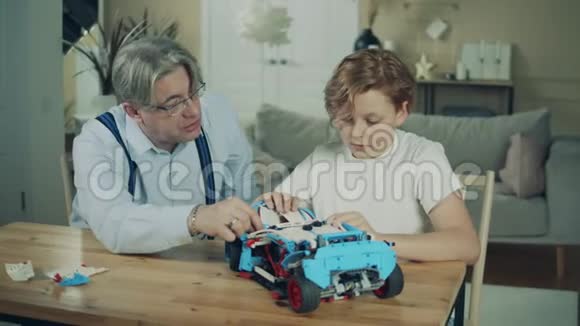 祖父和他的孙子正在组装一辆玩具车视频的预览图