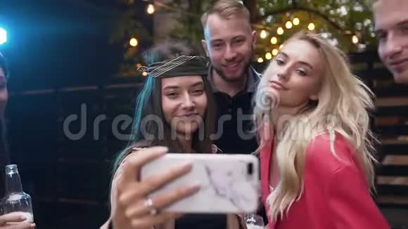 漂亮的兴高采烈的男女在女孩的手机上用有趣的脸自拍视频的预览图