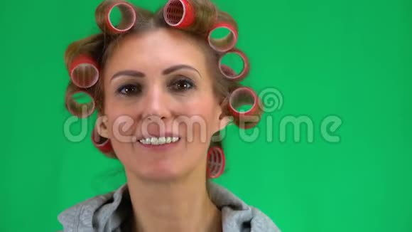 一个头上戴卷发的中年妇女试着戴上你的眼镜高兴起来女性面部特写背景是视频的预览图