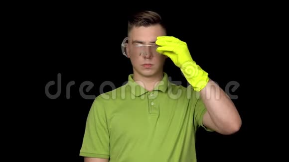 一个年轻的清洁工戴上眼镜手里拿着马桶刷人准备清洗戴安全眼镜的人视频的预览图