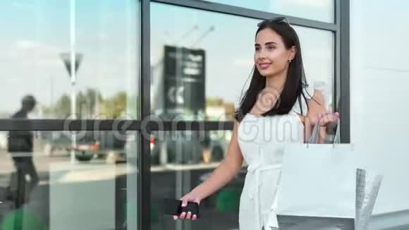 时尚女性模特享受购物使用智能手机步行户外稳定建立射击视频的预览图