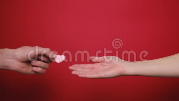 男性给女性手中的小白心孤立在红色背景上视频的预览图