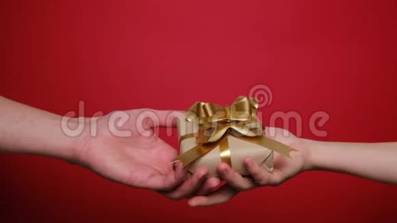 双手POV在红色背景上赠送手工礼品盒圣诞节情人节和生日概念视频的预览图