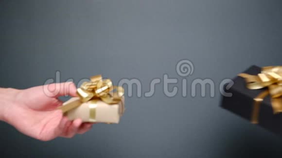 在灰色背景下一对年轻夫妇的双手献上各种手工礼品盒视频的预览图