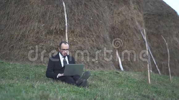 微笑男经理在山上的笔记本电脑上工作视频的预览图