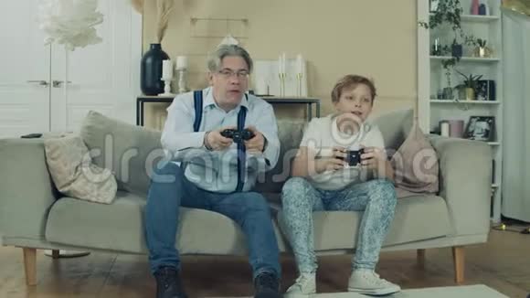 十几岁的男孩正在和他的爷爷玩电子游戏视频的预览图