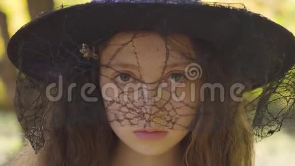 一个红头发的白种人女孩戴着万圣节女巫帽子站在秋天的公园里有卷发和棕色的孩子视频的预览图