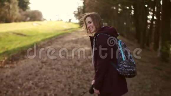 一个年轻的女人正在春天的城市公园里牵着狗的皮带散步那女孩穿着一件紫红色的夹克视频的预览图