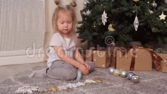 可爱的女孩数星星和球坐在家的圣诞树附近视频的预览图