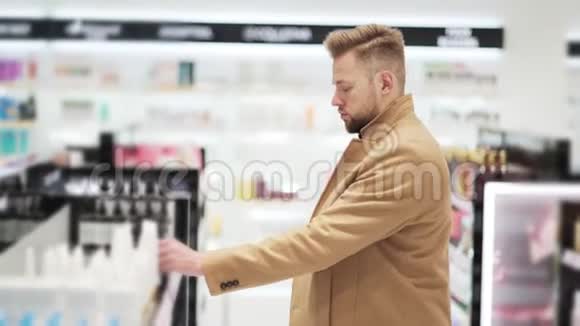 年轻的帅哥在化妆品店挑选商品购物理念视频的预览图