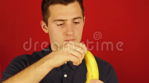 一个穿衬衫的男人在红色背景下打扫卫生吃香蕉视频的预览图