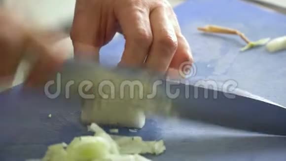 厨师在蓝色的切割板上切碎白色洋葱手的特写动作视频的预览图