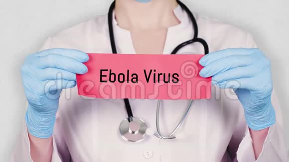 特写双手戴蓝色医用手套手持撕红纸卡上刻有埃博拉病毒字样穿着衣服的医生视频的预览图