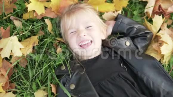 美丽的小女孩躺在地上秋天的视频的预览图