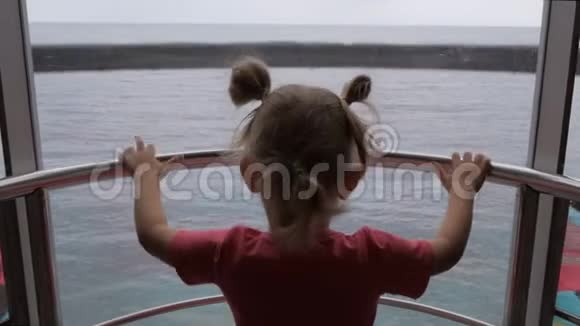 一个小女孩坐着透明的电梯上去俯瞰大海视频的预览图