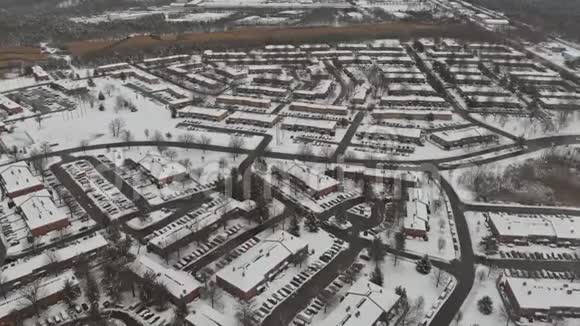 在大雪覆盖的城镇街道和房屋上飞行的空中景观视频的预览图