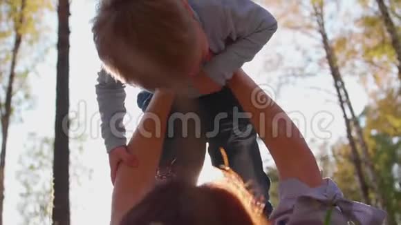 家庭幸福妈妈把儿子抱在怀里孩子笑了在太阳和天空的背景下快乐的孩子视频的预览图