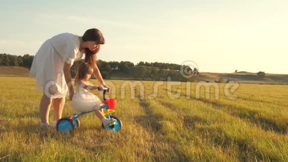 妈妈教女儿骑自行车女儿和母亲正在草地上玩耍妈妈玩她的小东西视频的预览图