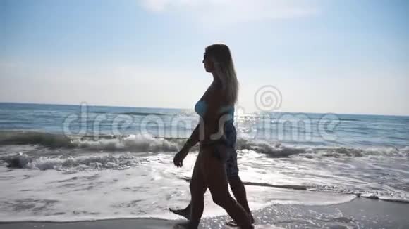 一对情侣在海滨度假时散步男人和女人漫步在海滩上享受视频的预览图