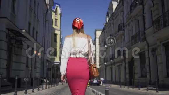 在街上走着的美丽年轻女子的后景中转过身来看着相机做着诱人的手势视频的预览图