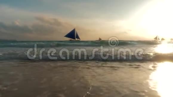 令人惊叹的热带日落色彩帆船的轮廓漂浮在海洋地平线上海浪洗沙Borac视频的预览图