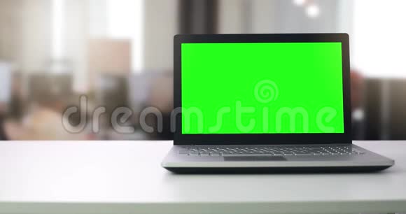 办公室桌子上有空白绿色屏幕的笔记本电脑视频的预览图
