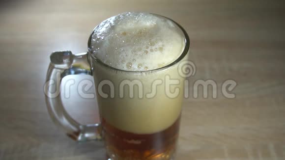 在新鲜的手工啤酒上有厚厚的泡沫气泡倒入一个带有把手的高玻璃杯中视频的预览图