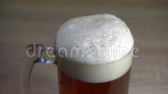 在新鲜的手工啤酒上有厚厚的泡沫气泡倒入一个带有把手的高玻璃杯中视频的预览图