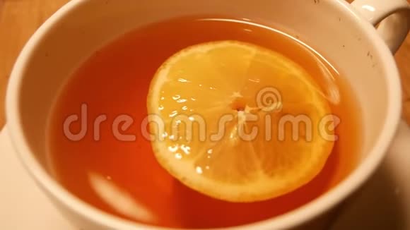 慢动作柠檬茶放在白色杯子里黄色的柠檬浮在水面上视频的预览图