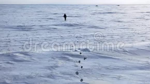 孤独的人走着扔着无边无际的雪沙漠视频的预览图