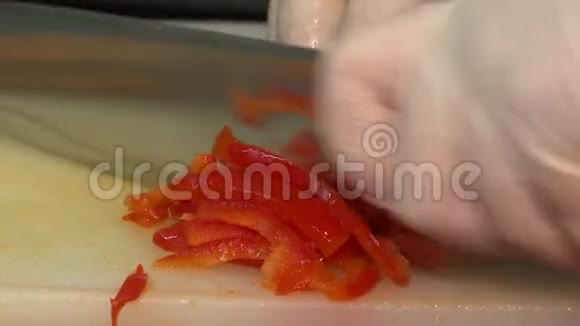 厨师用刀子在厨房的切割板上切红辣椒视频的预览图