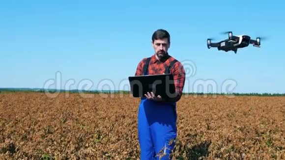 无人机正在一个携带笔记本电脑的农业技术人员附近飞行视频的预览图
