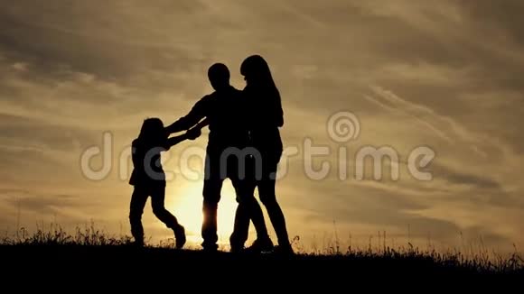 幸福的家庭在日落时牵手一起在户外玩视频的预览图