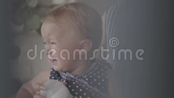 一个美丽的女婴坐在妈妈怀里哭特写一个女人想喂她淘气的孩子概念视频的预览图