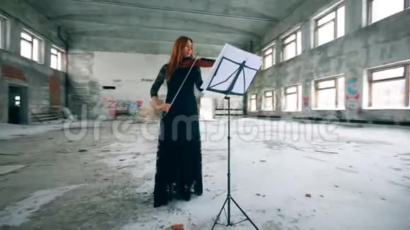 一位女士正在一座搁浅的大楼里拉小提琴视频的预览图