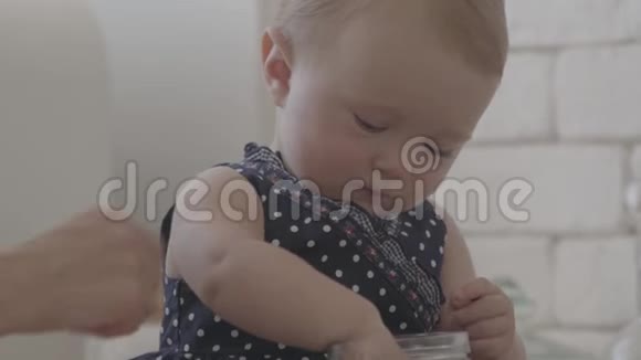 当她妈妈的手在帮她的时候她紧紧地抱着孩子玩麦片粥厨房里的年轻女子视频的预览图