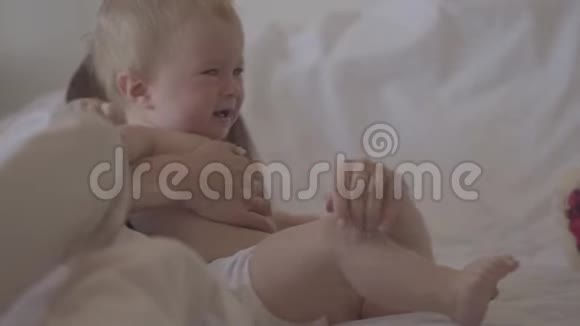 一个美丽的女婴躺在床上在母亲的怀里哭泣一个女人试图安抚她顽皮的孩子视频的预览图