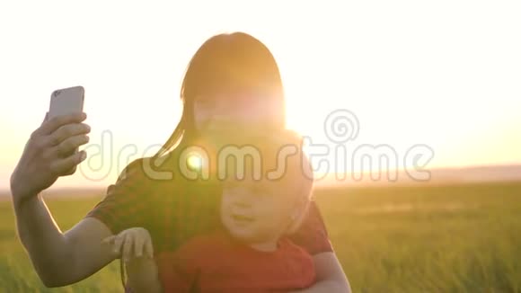 一位年轻漂亮的母亲和女儿用智能手机自拍坐在草地上微笑视频的预览图