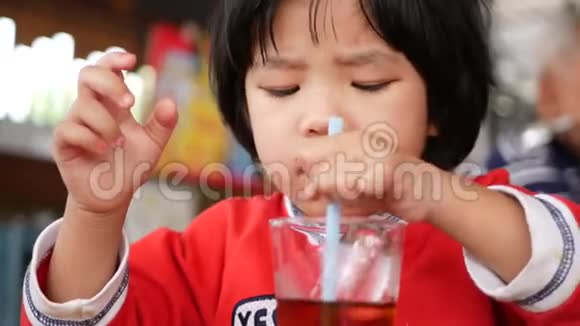 小亚洲小女孩在喝汽水的时候玩钢笔宝宝在探索周围的事物视频的预览图