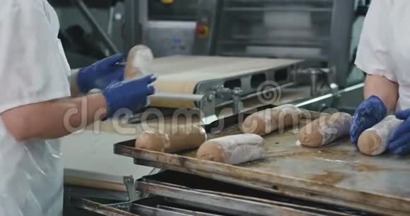 在一家大型的商业厨房面包店里工人们从面团中成型美丽的生面包准备烤进烤箱视频的预览图